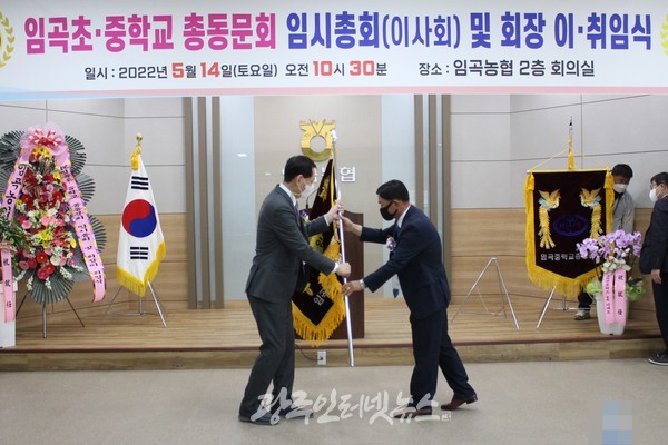 이임하는 제5대 기성종 회장이 신임 6대 김태수 회장에게 동문회기를 전달하고 있다.